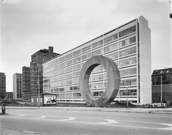Afbeelding uit: juli 1991. De inmiddels verdwenen witte vleugel. Het betonnen kunstwerk op de voorgrond heet Gebroken Cirkel, is gemaakt door Ad Dekkers en stond hier van 1976 tot 2003. Het staat nu aan de Nieuwe Hemweg.