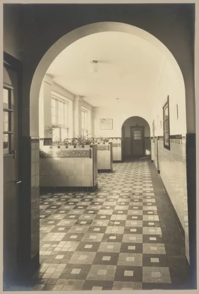 Afbeelding uit: circa 1932. Een van de gangen, met nissen voor de jassen.
Bron afbeelding: SAA, bestand ANWR00029000003.