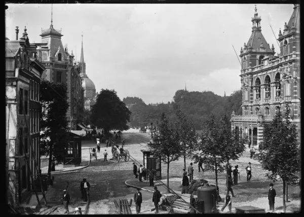 Afbeelding uit: juli 1900. Links op de voorgrond werkzaamheden voor de bouw van het politiebureau. Het pand dat gestut wordt, is Leidseplein 19.