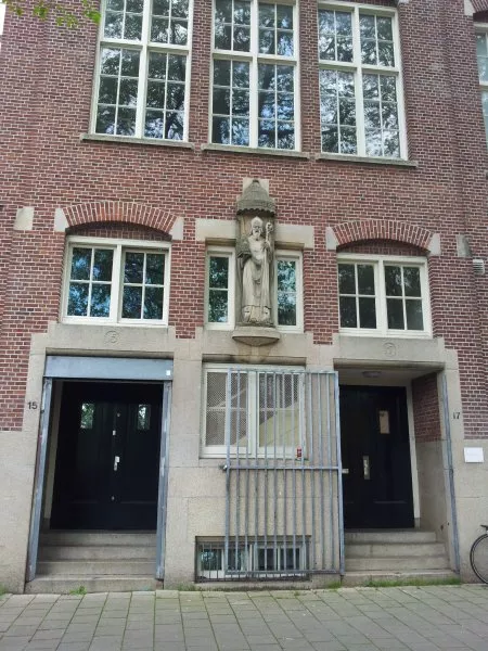 Afbeelding uit: augustus 2011. Links de ingang van het patronaat, rechts die van de school. Het beeld van de heilige Willibrordus kwam er op het verzoek van een de mensen die geld schonken voor de bouw van de school.