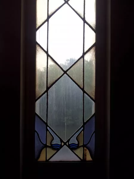 Afbeelding uit: september 2011. Gebrandschilderd raam in het trappenhuis, met onderin twee scheikundig ogende glazen vaten.