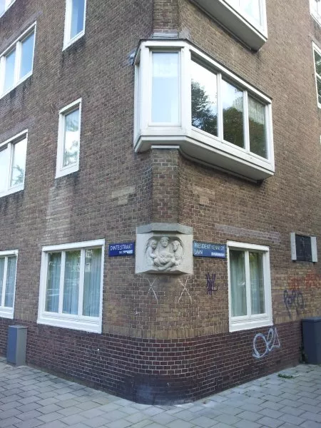 Afbeelding uit: september 2011. De sculptuur op de hoek Dintelstraat - Kennedylaan is van de hand van Jan Schultsz. Gemaakt in 1933, van graniet. Een zittende man met een kind en een lam aan zijn zijde. Tekst: "Zuid 1930".