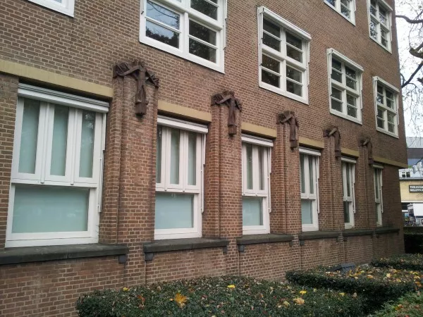 Afbeelding uit: november 2013. "Op de muurdammen tussen de vensters figuratieve bouwceramiek, verwijzend naar de oorspronkelijke bestemming van het gebouw."