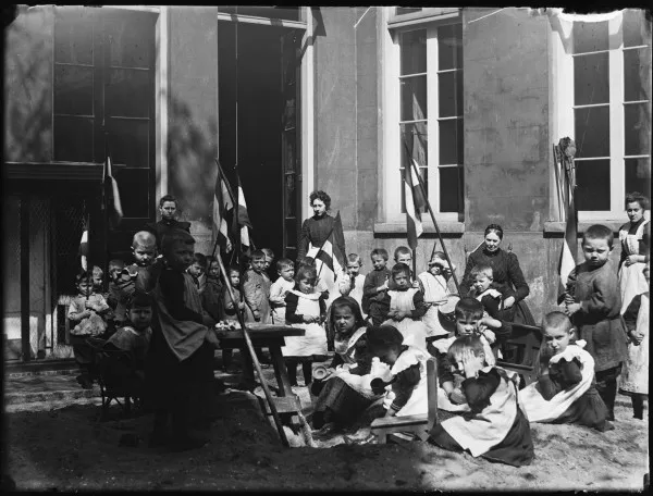 Afbeelding uit: mei 1900. Bezoekers en begeleidsters van de bewaarschool.