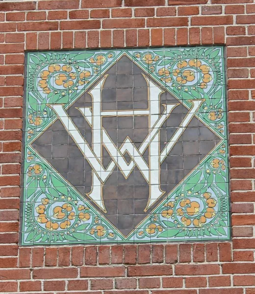 Afbeelding uit: augustus 2014. Tegeltableau met het monogram 'HWV' op een blok woningen aan de Maritzstraat.