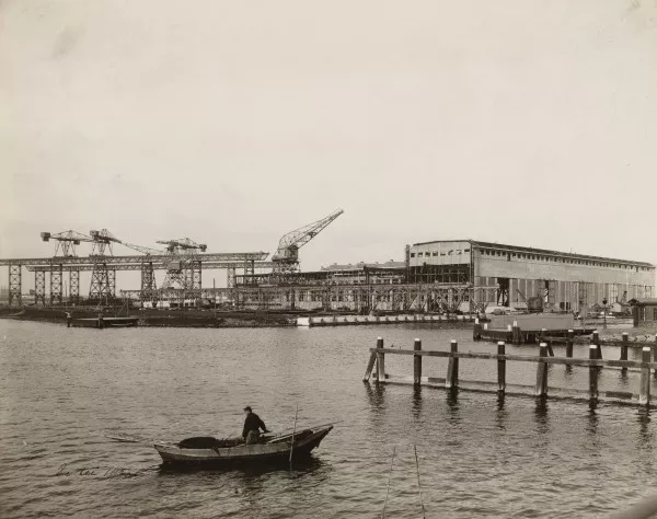 Afbeelding uit: mei 1922. Rechts de grote scheepsbouwloods, links kraanbanen langs de hellingen. Op de voorgrond een visser op het water van Zijkanaal I.