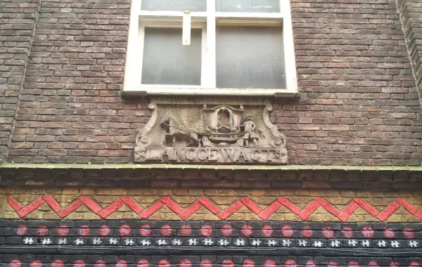 Afbeelding uit: maart 2015. Gevelsteen met de tekst "Lang gewagt" en een toeslede, een koets op een slee. De steen komt van het 18de-eeuwse huis Wijdesteeg 17, dat hier tot 1932 stond maar gesloopt werd nadat de woningen onbewoonbaar waren verklaard.