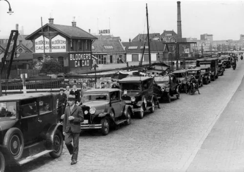Afbeelding uit: jaren '30. Een rij auto's op de Weesperzijde. Links aan de overkant van het water het Blookerhuisje.