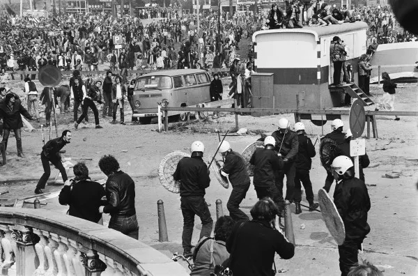 Afbeelding uit: april 1980. Krakers en sympathisanten die naar de Dam willen tegenover de oproerpolitie. Op de dag van de inhuldiging van koningin Beatrix werd er op en rond de brug flink gevochten.