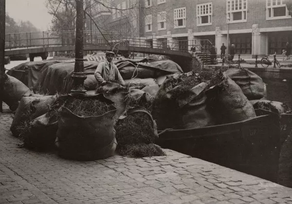 Afbeelding uit: circa 1930. Tabak werd per schuit aangevoerd naar de veiling over de Oudezijds Voorburgwal.
Bron afbeelding: SAA, bestand OSIM00002003122.