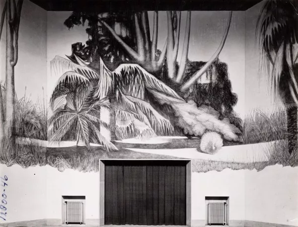 Afbeelding uit: circa 1940. De achterwand van de zaal, met muurschildering gemaakt door Albert Muis. De uitgang leidde naar het kerkhof.
Bron afbeelding: SAA, bestand 010009011561.