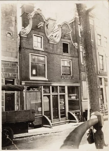 Afbeelding uit: december 1927. De huizen vóór de herbouw. 309 (links) stond leeg en was te koop. Op 311 verkocht de firma P. Geervliet hoortoestellen en kerktelefoons.
Bron afbeelding: SAA, bestand 012000007077.