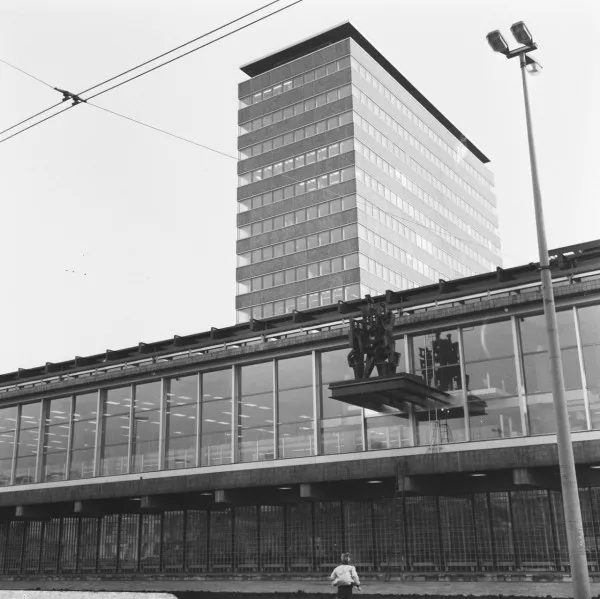 Afbeelding uit: november 1967. Het kunstwerk La Demeure Humaine (het menselijk verblijf) van Ossip Zadkine op de oorspronkelijk plek, aan de gevel aan het Frederiksplein. In 1990 werd het hier verwijderd en herplaatst op een grote tafel op de stoep van het Westeinde. Het staat nu naast de hoofdingang.