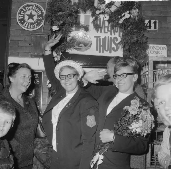 Afbeelding uit: oktober 1964. De zwemmende zussen Gretta (links) en Ada Kok worden feestelijk onthaald bij hun ouderlijk huis op nummer 41. Op de Olympische Spelen in Tokio had Ada een zilveren medaille gewonnen.