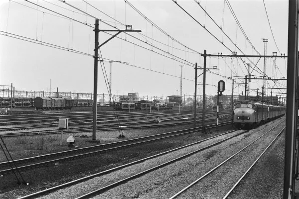 Afbeelding uit: juli 1982. Foto gemaakt toen het emplacement nog een rangeerterrein was. De trein rechts rijdt op de lijn Amsterdam-Hilversum.