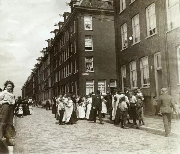Afbeelding uit: 1911. De hoek met de Conradstraat in 1911, ten tijde van een staking van zeelieden. Buurtbewoners bespreken de situatie.