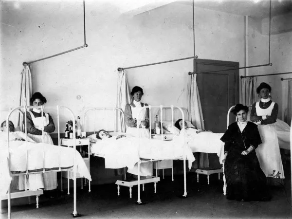 Afbeelding uit: 1909. Patiënten, zusters en een bezoekster in een ziekenzaal.
