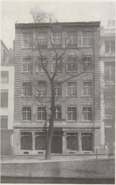 Afbeelding uit: circa 1915. Boven de ramen links staat "N.V. v/h Hoeker en Zoon". Rechts: "Opg. C.A. Volk 1840".