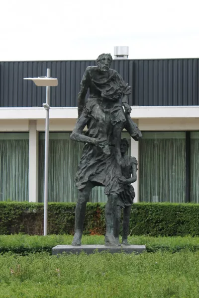 Afbeelding uit: juni 2018. In het plantsoen rechts van de hoofdingang staat het beeld Enea van Sandro Chia uit 1999. Het stelt Aeneas voor, de Griekse halfgod die het brandende Troje ontvluchtte met zijn vader op zijn schouders en zijn zoon aan zijn hand.