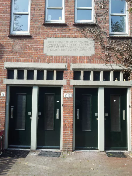 Afbeelding uit: maart 2012. Het gedicht op de steen is van David Ingwersen, broer van architect Ingwersen, en refereert aan de moeilijke tijden waarin de wijk gebouwd werd. Elders in de straat bevindt zich nog een gedicht.

"Omhoog rees Noachs ark op tuimelende vloeden,
Waarover bliksem flitst en harde donder knalt.
Zoo rees in oorlogstijd, toen wereldstormen woedden,
Dit bouwwerk blij omhoog, van Godes schuts omwald."