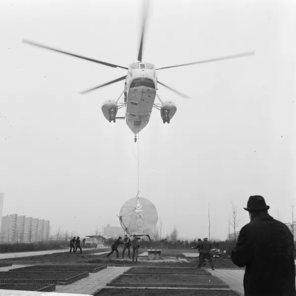 Afbeelding uit: maart 1969. Met hulp van een helikopter wordt het kunstwerk The long hum van Theo Niermeijer geplaatst op  Enzerinck-oost.