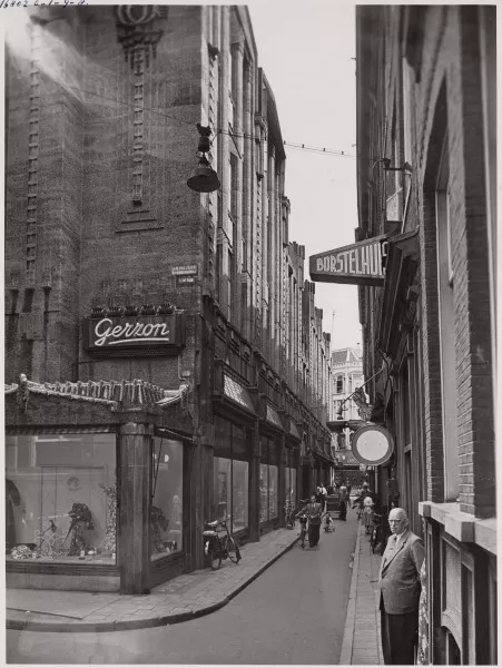 Afbeelding uit: circa 1950. Sint Luciënsteeg, gezien richting Kalverstraat. Er waren nog etalagekasten op de hoek.
Bron afbeelding: SAA, bestand 010009000361.
