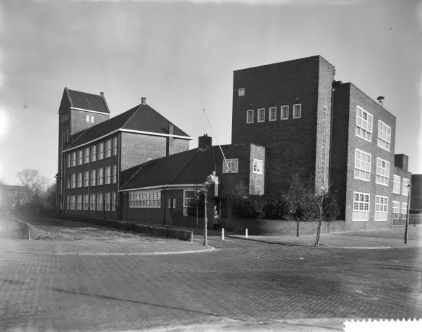 Afbeelding uit: januari 1961. Het gebouw rechts, in de stijl van de Amsterdamse School, is de voormalige Graaf Willem Lodewijk School uitgaande van de vereniging voor Gereformeerd Onderwijs; later de Openbare voorbereidende ULO "Adama van Scheltemaschool".