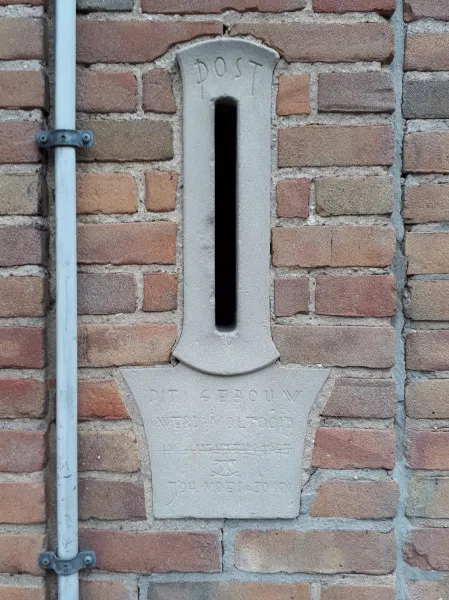 Afbeelding uit: januari 2019. Brievenbus, met daaronder de inscriptie "Dit gebouw werd voltooid in augustus 1948 [symbool] Joh. Moes & Zonen".
