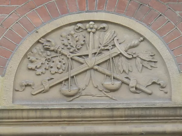 Afbeelding uit: augustus 2019. Reliëf met symbolen van justitie, op het voormalige kantongerecht aan het Kleine-Gartmanplantsoen.