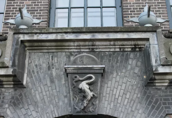 Afbeelding uit: januari 2014. Symboliek op de kazerne aan de De Ruijterkade. Van salamanders werd ooit gedacht dat ze onkwetsbaar waren door vuur omdat ze er zelf uit geboren waren.