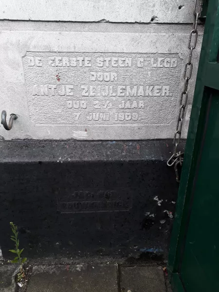 Afbeelding uit: september 2019. Onder, in het zwart: "Jac. Bas / bouwkundige"
Boven, in het wit: "Eerste steen gelegd / door / Antje Zeijlemaker / oud 2½ jaar / 7 juni 1909."