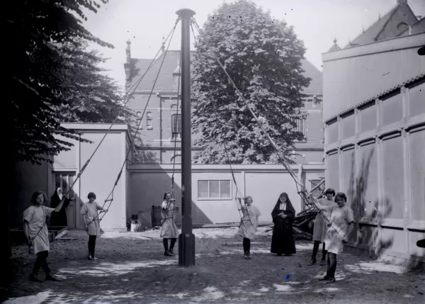 Afbeelding uit: 1920. Kinderen spelen aan een zweefmolen in de tuin van het tehuis. Vermoedelijk zijn het weeskinderen uit het aan het gesticht gelieerde Maagdenhuis. Foto collectie RCE/Brinio, obj.nr BR00406-DOOS21.