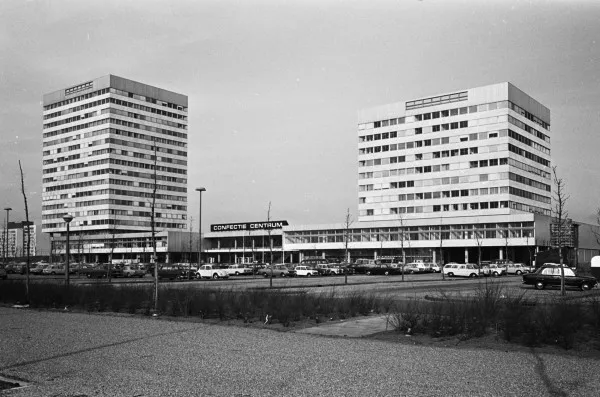 Afbeelding uit: maart 1968. Het oorspronkelijke gebouw, met twee torens. Op de voorgrond het inmiddels bebouwde parkeerterrein.