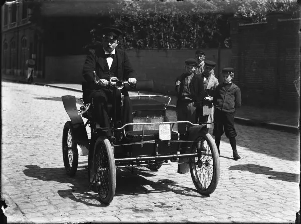Afbeelding uit: juni 1899. J. Leonard Lang, later een van de grootste autodealers van de stad, poseert op zijn Decauville, in de Huidekopersstraat.