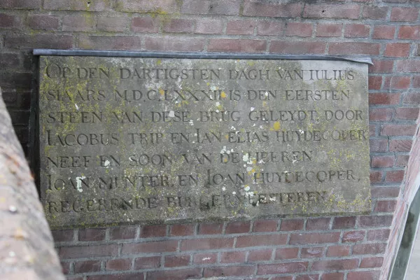 Afbeelding uit: april 2020. Deze gedenksteen uit 1682 herinnert aan het leggen van de eerste steen van de toenmalige sluis. In 2015 werd ze ingemetseld in het meest oostelijke landhoofd van de huidige brug, aan de kant van het Oosterdok.
