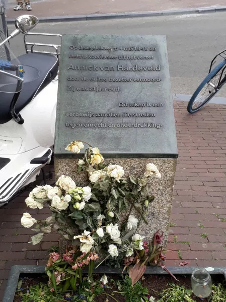 Afbeelding uit: mei 2020. Op het Hekelveld staat dit zuiltje, met een plaquette ter nagedachtenis van Annick van Hardeveld (dochter van de architect Van Hardeveld). Zij was een 21-jarige koerierster voor het verzet, en werd hier vlak voor het einde van de oorlog door de Duitse bezetter doodgeschoten.