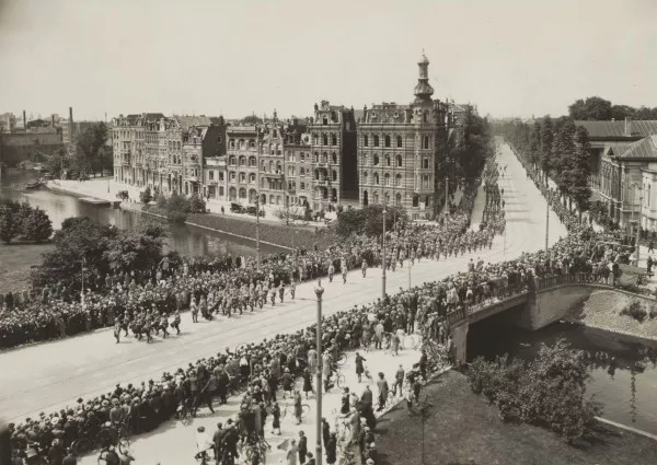 Afbeelding uit: juni 1927. De begrafenisstoet van generaal Van Heutsz passeerde het hoekhuis. De foto is gemaakt vanaf de Muiderpoort.
