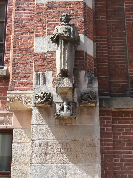 Afbeelding uit: juni 2021. Warmoesstraat. Gedenksteen voor de dichter Vondel (1587-1679), die een tijd lang op het verdwenen nummer 110 woonde en werkte. Het beeld is in 1937 gemaakt door Gerarda Rueter.