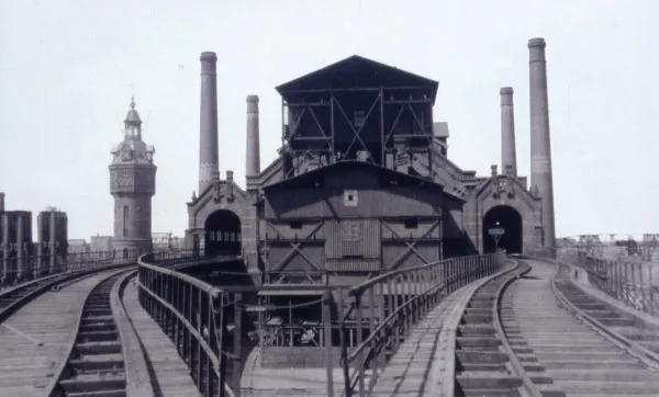 Afbeelding uit: onbekend. Het oostelijke retortengebouw, oftewel de stokerij. Kolen werden per spoor aangevoerd. Links de watertoren.