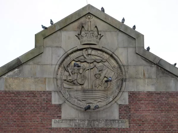 Afbeelding uit: januari 2022. Gevel Beursplein. Onder het oude stadswapen (de kogge) staat "Deze beurs werd voltooid in het jaar 1902".