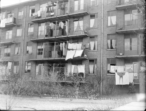 Afbeelding uit: maart 1943. Voor veel bewoners waren de aparte was-secties op de balkons niet toereikend, zodat er tegen de zin van de architecten in toch wasgoed aan balkons wapperde.
Bron afbeelding: SAA, bestand 5293FO006052.