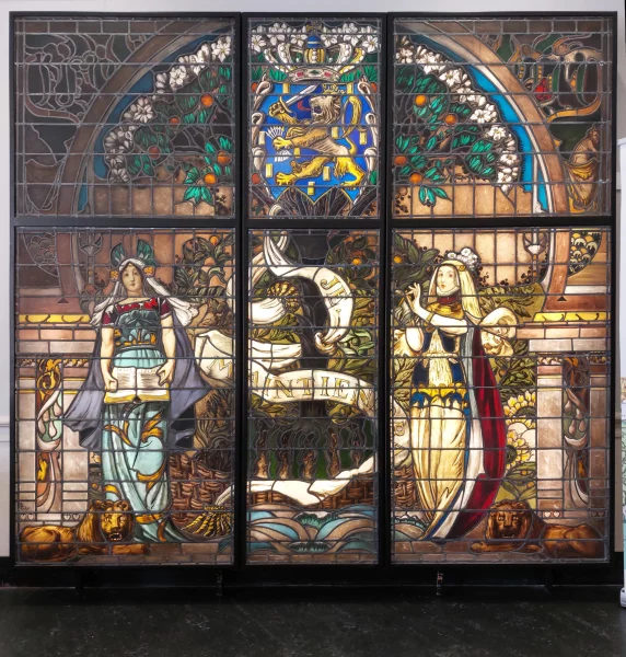 Afbeelding uit: juli 2023. In de hal bij de huidige entree staat een groot gebrandschilderd raam uit 1903, gemaakt door glazenier Jan Schouten naar een ontwerp van Adolf le Comte.