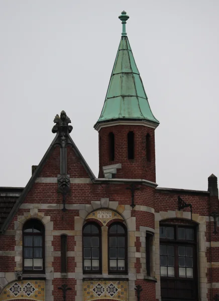 Afbeelding uit: december 2023. De geveltop met torentje en de tekst "Anno 1899".