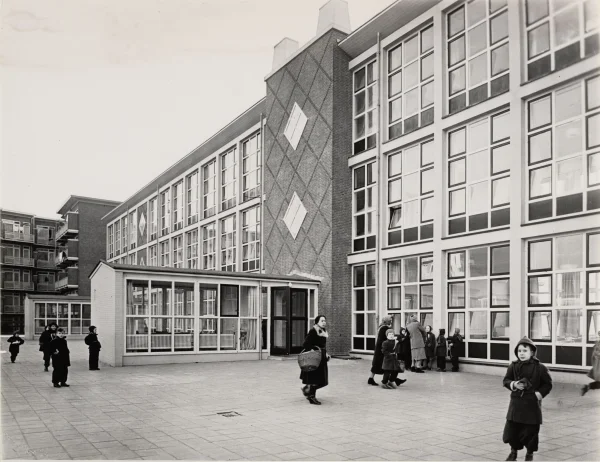 Afbeelding uit: circa 1955. Achterzijde. In de uitbouwtjes waren de werkkamers van de schoolhoofden.
Bron afbeelding: SAA, bestand 010009011449.
