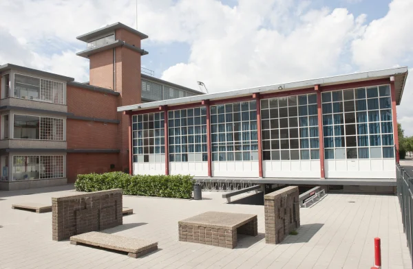 Afbeelding uit: juli 2012. Op de voorgrond de zgn. kletsmuurtjes van Ch.J.F. Karsten: muurtjes, banken en tafels met abstracte afbeeldingen in reliëf van baksteen en beton. Collectie RCE Amersfoort, doc.nr 10870-9930.