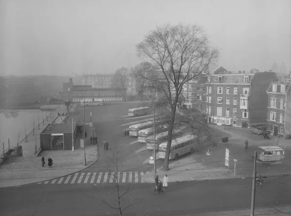 Afbeelding uit: 1957. Het busstation was er al vóór de bouw van de parkeergarage. Rechts de achterzijde van de huizen die oorspronkelijk aan de Marnixstraat stonden. (Collectie Noord-Hollands Archief, inv.nr NL-HlmNHA_1478_16397B01_01)