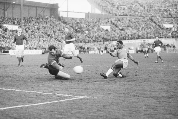 Afbeelding uit: mei 1963. Het Nederlandse elftal speelde op 2 mei 1963 tegen wereldkampioen Brazilië. Doelman Eddy Pieters Graafland weert hier een Braziliaanse doelpoging (van Ney de Oliviera?). Ton Pronk en Jan Klaassens kijken toe. (Collectie Noord-Hollands Archief, inv.nr NL-HlmNHA_1478_00761K03_04)