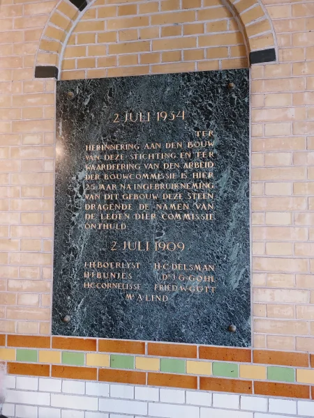 Afbeelding uit: april 2024. Plaquette in de hal, geplaatst 25 jaar na de bouw.