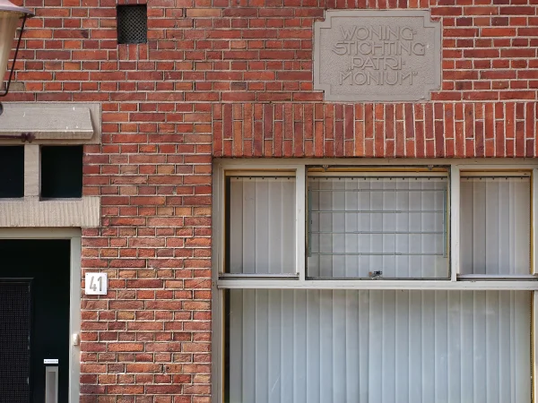 Afbeelding uit: juli 2016. Steen met de naam van de woningstichting, in de voorgevel van Zwanenplein 41.