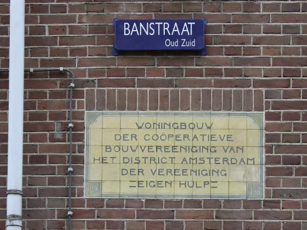 Afbeelding uit: oktober 2024. Plaquette in een muur van het eerste project van Eigen Hulp aan de Banstraat.